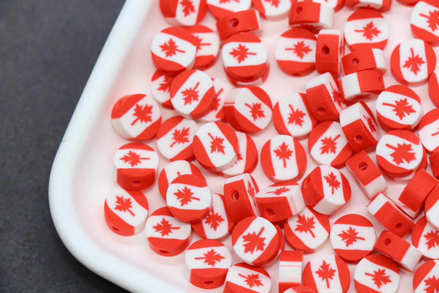 Red and white beads with a maple leaf pattern on a white container.