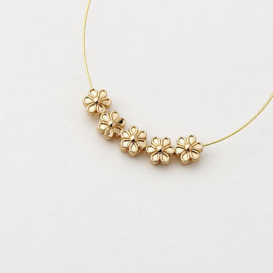 May include: A thin gold wire hoop earring featuring five small, identical gold flower-shaped charms strung along the bottom curve. Each flower charm has six rounded petals and a central dot, creating a delicate and uniform metallic design.