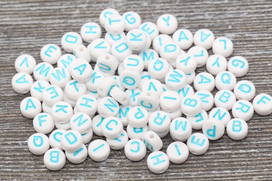 A pile of round white beads with blue letters on a wooden surface.