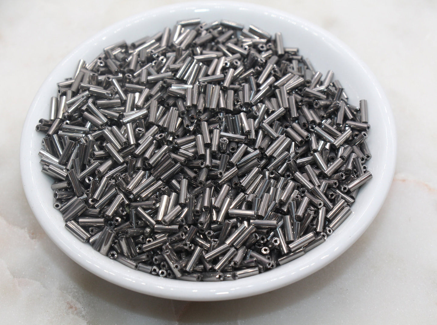 6mm Gunmetal Bugle Beads, perfect for embellishing clothing, accessories, and craft projects.