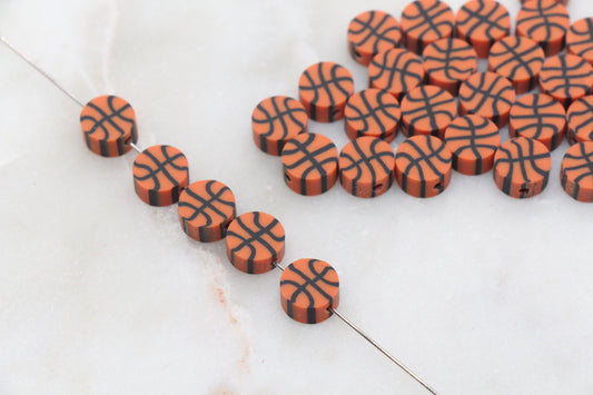 Orange basketball-shaped beads on a string against a white background.