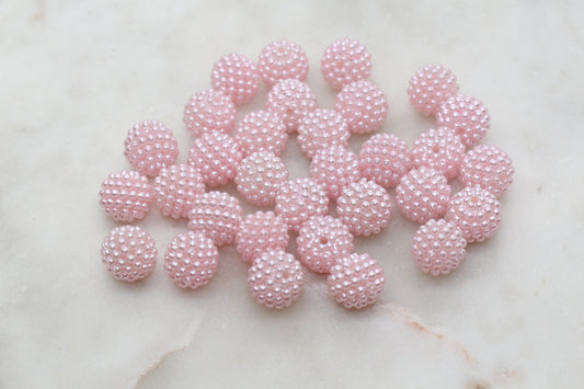 A cluster of pink beaded balls on a pale surface.