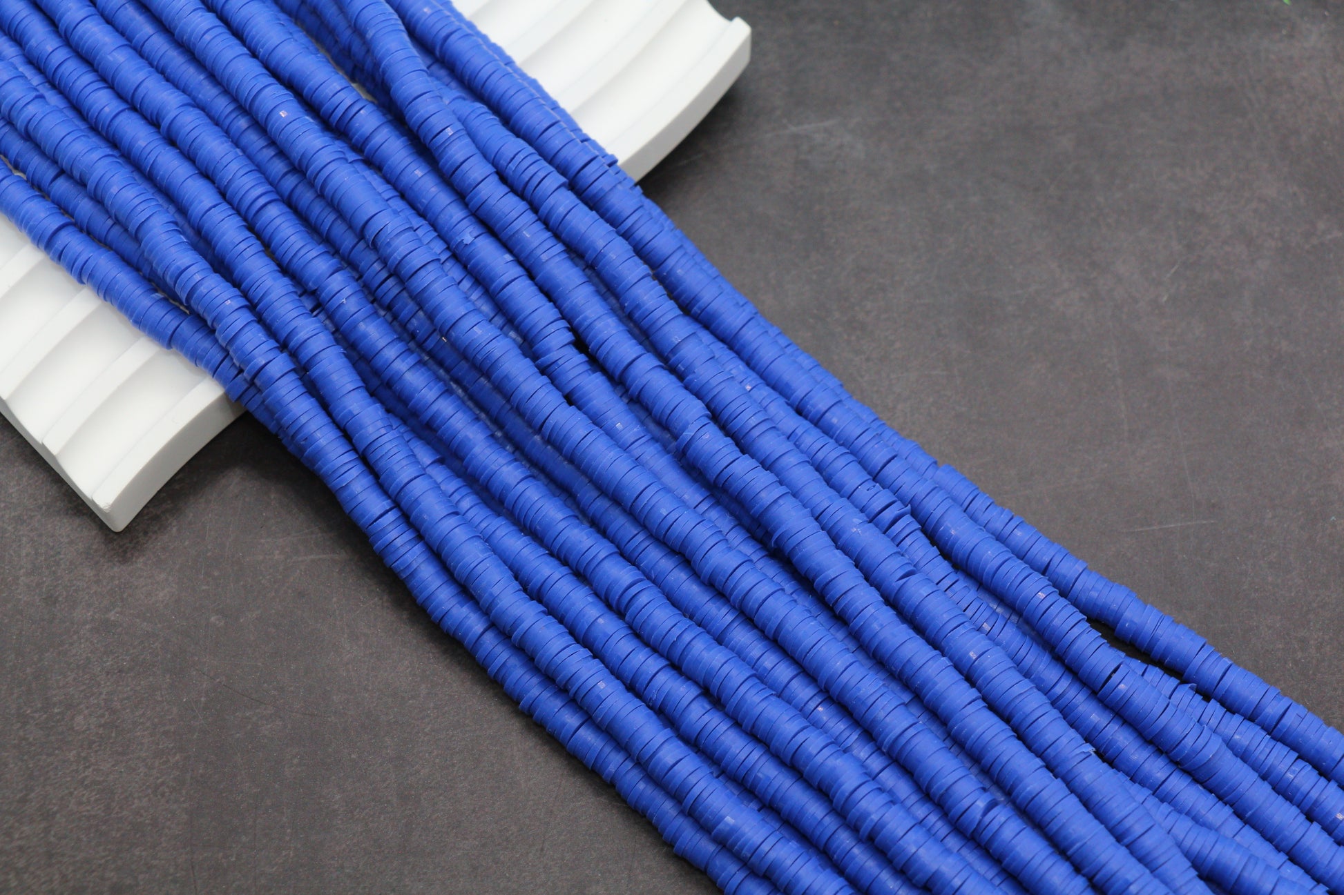 Close-up of blue heishi beads on a dark surface