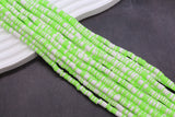 Green and white striped beads on a dark surface