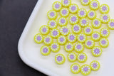 Yellow and purple circular candies on a white plate with a dark background
