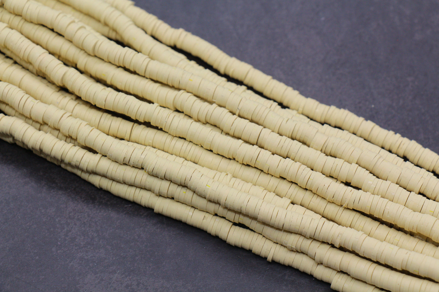 Beige heishi beads on a dark gray background