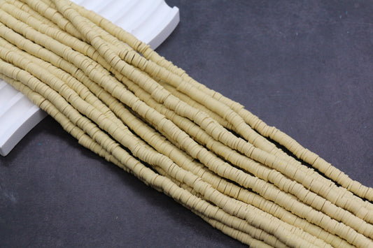 Beige heishi beads on a dark surface