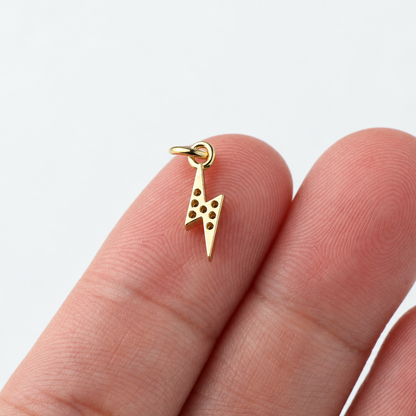 Back of gold-plated lightning bolt charm with attached jump ring on fingertips
