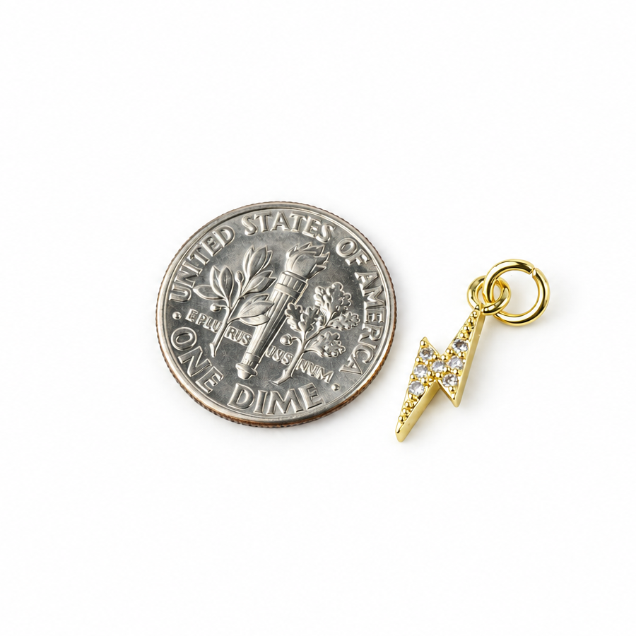 Small gold-plated CZ lightning bolt charm beside a dime for scale