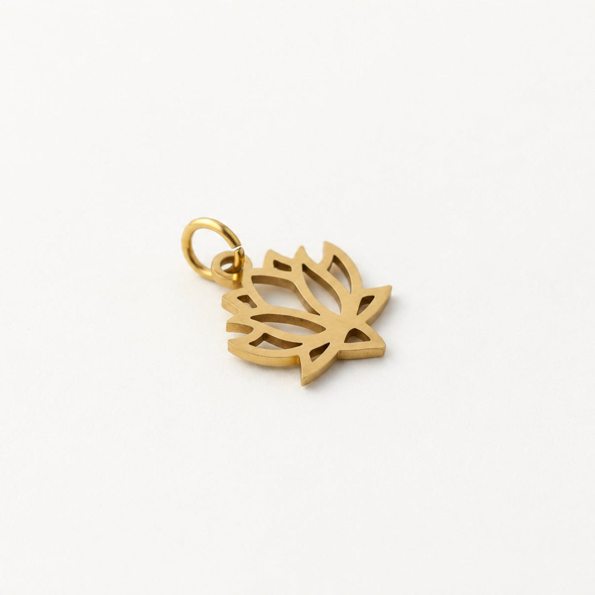 Angled gold-plated stainless steel openwork lotus pendant with attached jump ring on neutral ivory background