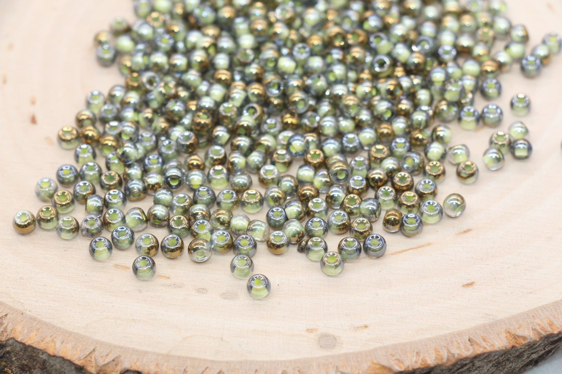 Scattered shiny green beads on a wooden surface.