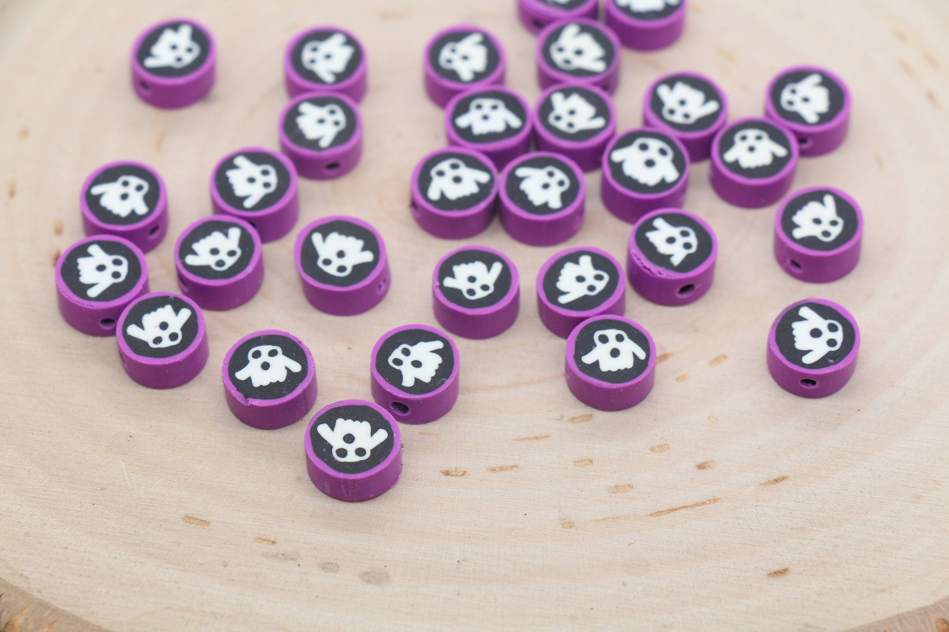 Purple beads with white paw print designs scattered on a wooden surface.