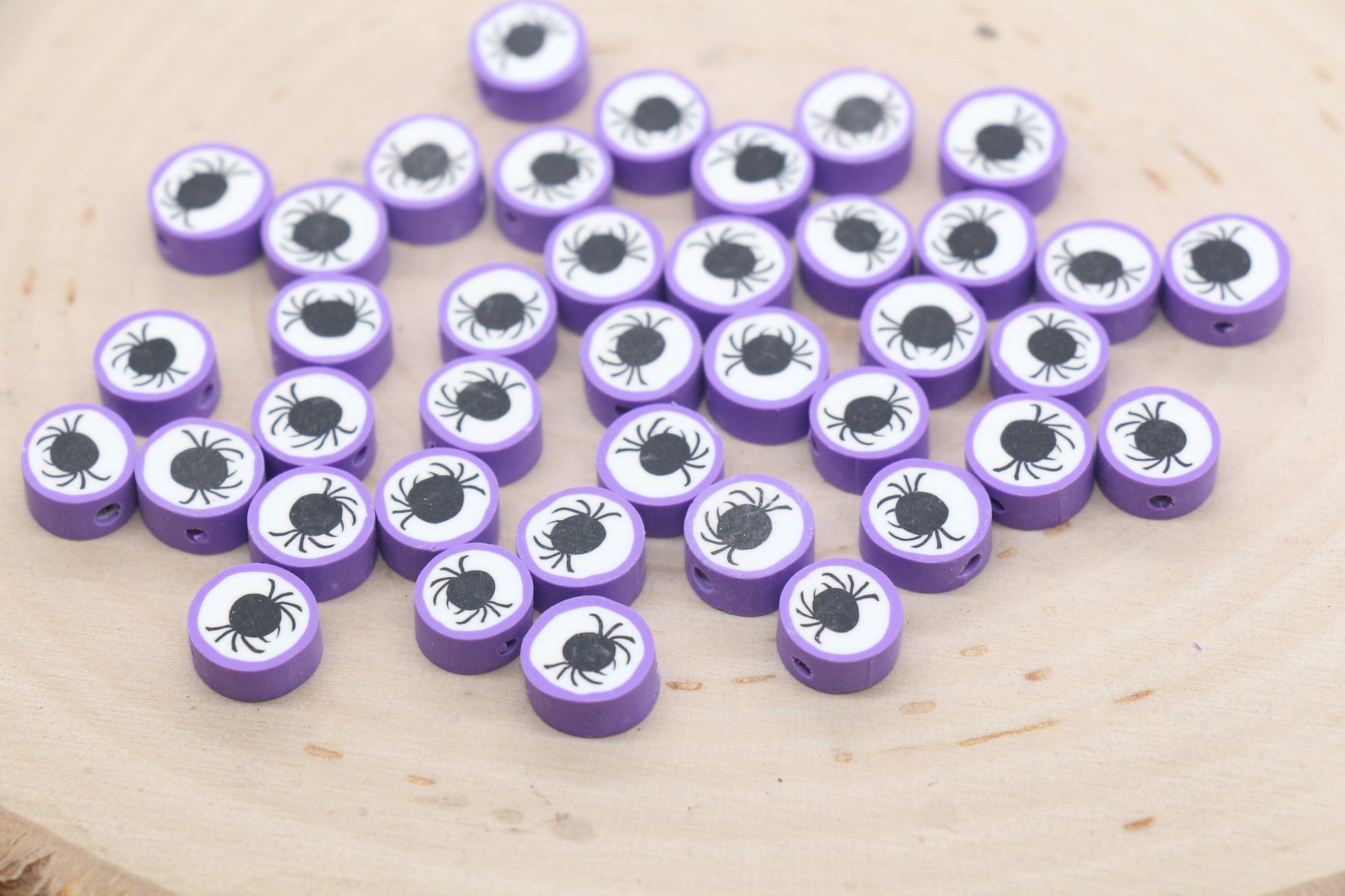 Purple tokens with eye and spider designs on a wooden surface.