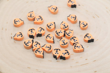 Orange and black pumpkin-shaped beads arranged in a circle on a white surface.