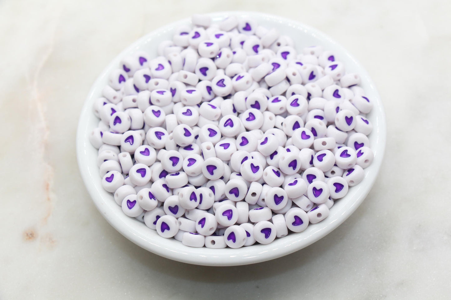 white beads with purple hearts in the center. Great for jewelry making and craft projects.