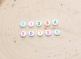 individual 7 mm round acrylic number beads, multicolor on white; multicolor number beads