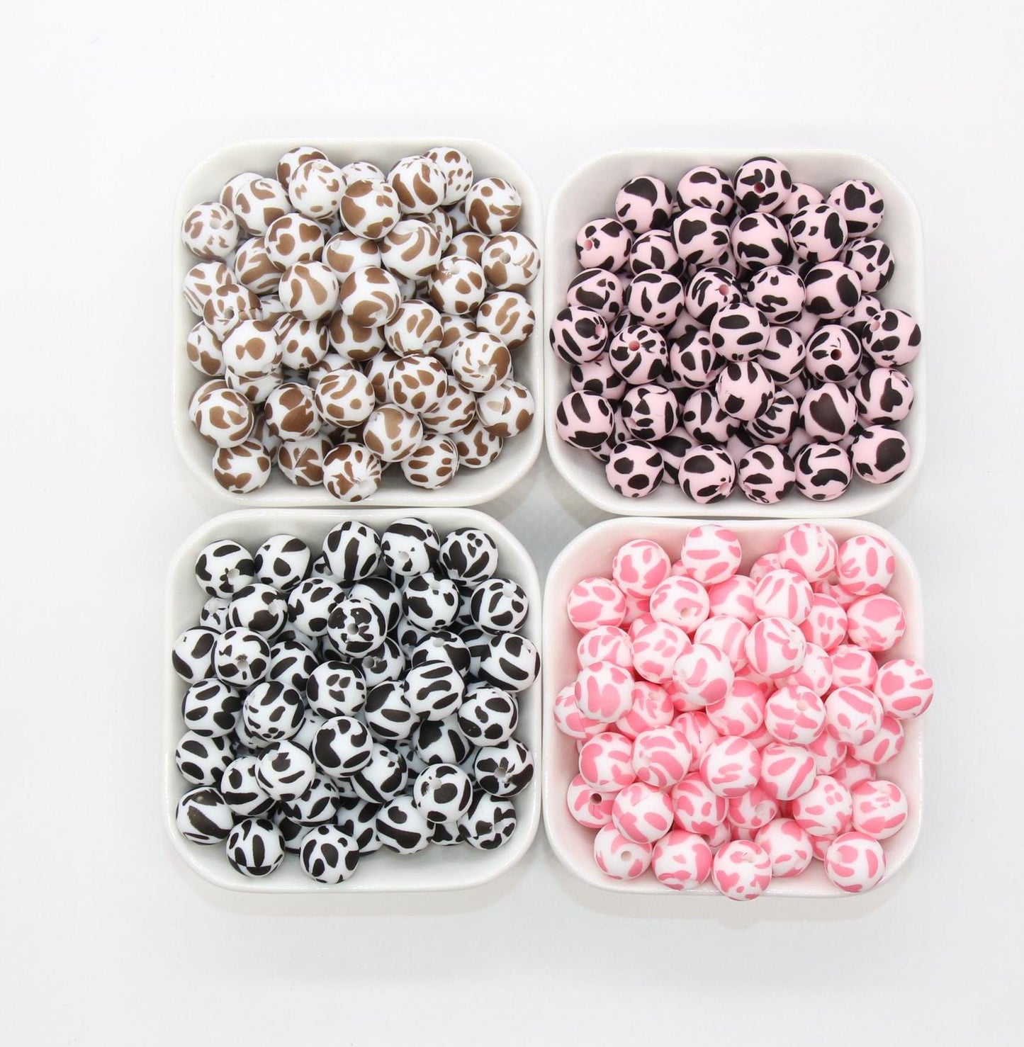 Four bowls with black and white, pink, brown, and black beads with animal-like patterns.