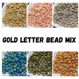 Mixed gold letter beads in assorted colors including beige, pink, gray, blue, green, and terracotta — round alphabet beads for jewelry making.