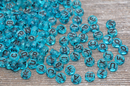 Blue alphabet beads scattered on a wooden surface.