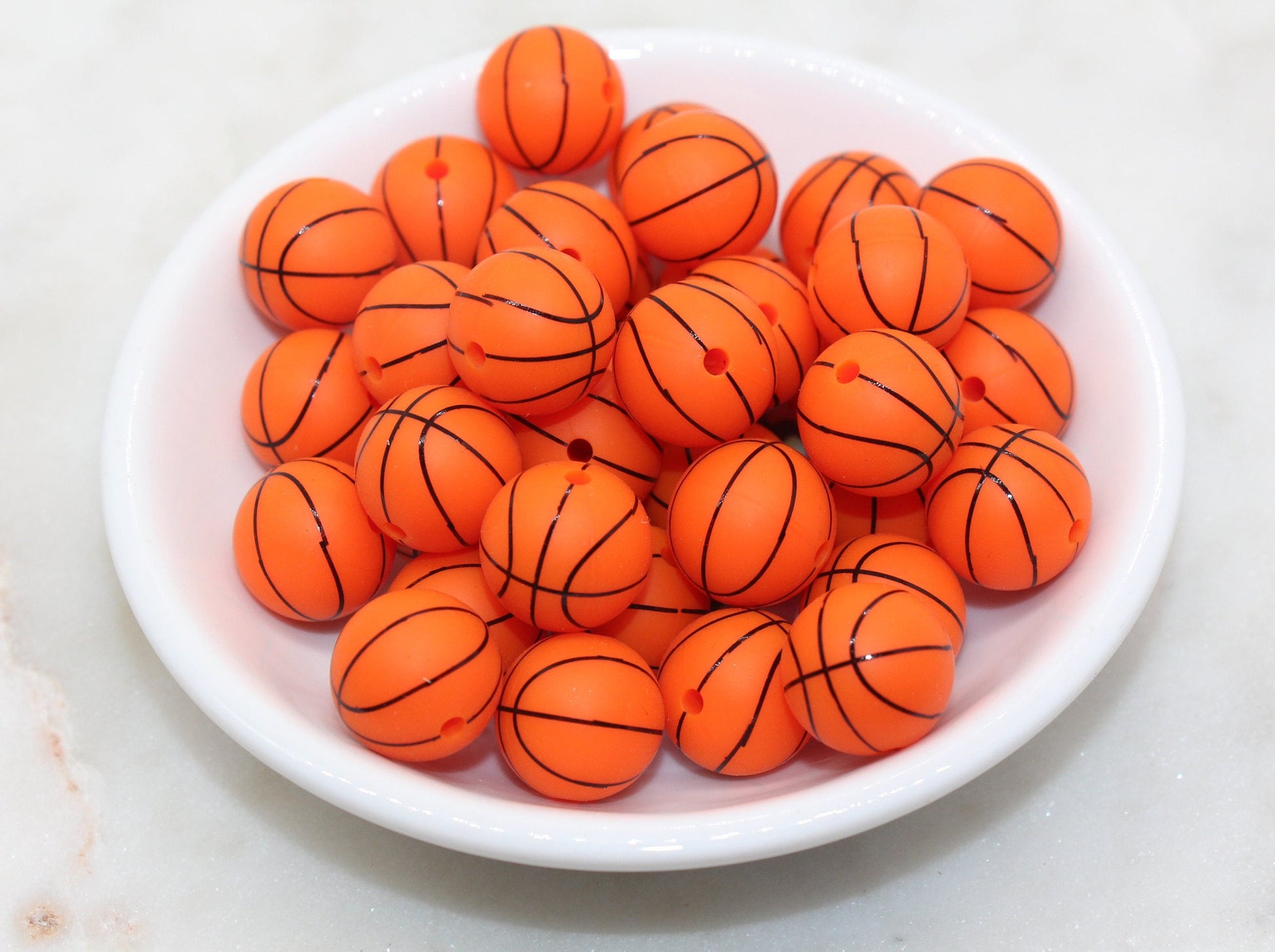 A bowl filled with miniature basketballs on a white surface.