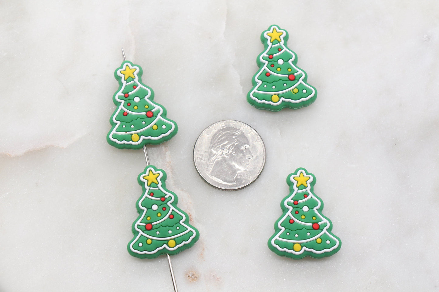 Four Christmas tree cookies with a quarter for size comparison.