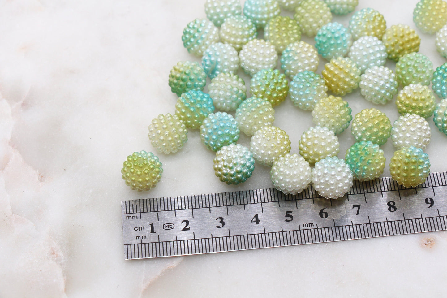 Multicolored round beads scattered near a ruler on a white surface.